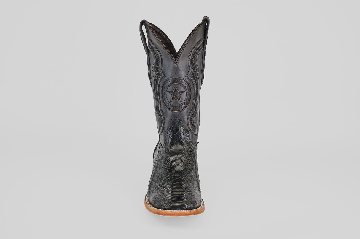 The Austin Leg - Black - Square Toe boot features decorative stitching, a star emblem on the shaft, and a light tan sole. Photographed from the front on a plain light gray background, it's ideal for square toe boot enthusiasts.