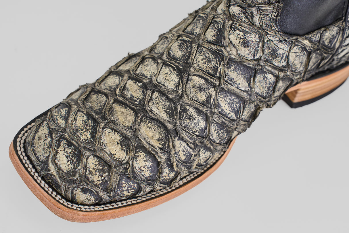 A close-up of the Conor - Rustic Bone - Square Toe men's cowboy boot, featuring textured exotic leather, detailed stitching, and a light tan sole.