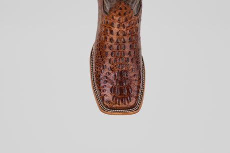 A close-up of the Hornback Brown - Embossed Leather - Square Toe (E427) boot highlights detailed stitching and its western square-toe style against a plain light background.