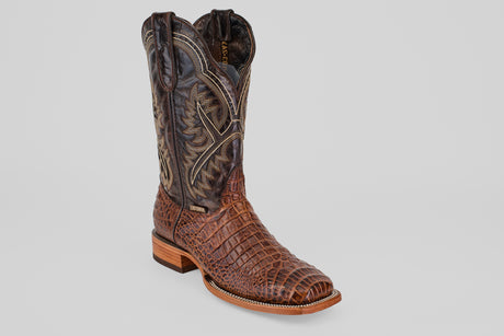 A single Caiman Belly Choco - Embossed Leather - Square Toe (E423) boot, brown with textured reptile-like pattern and detailed stitching, features a square toe and wooden heel, displayed on a plain gray background.