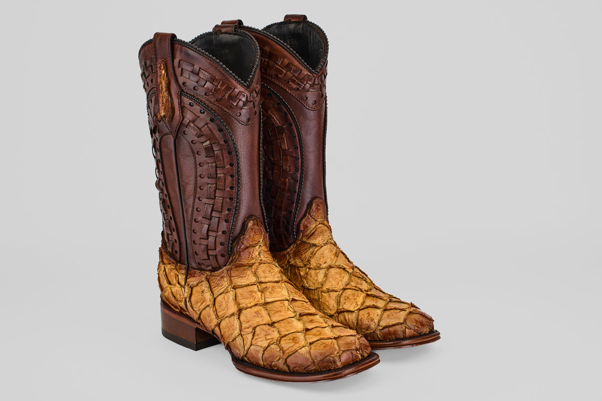 The Conor Platinum - Buttercup - Square Toe (Herradura) boots feature dark brown leather uppers with detailed stitching and light tan pirarucu leather lowers with a scale-like texture, displayed on a plain gray background.