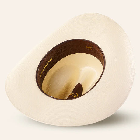 The 30x Sinaloa Straw Hat features a wide brim for sun protection and a brown inner band with gold lettering, making it ideal for outdoor adventures.