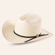 The 30x Sinaloa Straw Hat features a wide brim and black band for excellent sun protection. With a small round metal accent, this light-colored cowboy hat is perfect for outdoor adventures and is set against a plain light background.