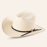 The 30x Sinaloa Straw Hat features a wide brim and black band for excellent sun protection. With a small round metal accent, this light-colored cowboy hat is perfect for outdoor adventures and is set against a plain light background.