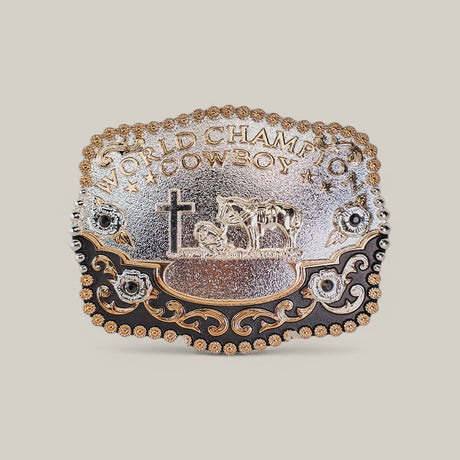 The Square Rose Gold Cattle Cross - Buckle features a Texas-style design in gold and alpaca silver, engraved with World Champion Cowboy. It showcases a horse, rider, and cross design with floral embellishments and western scrolling patterns.