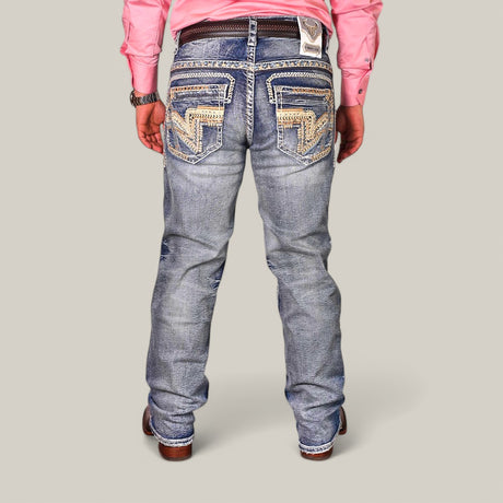 A person stands against a plain background, facing away from the camera, wearing Western Blue Straight Fit Embroidered Jeans WJ-2345 with intricate stitching on the back pockets, paired with a pink long-sleeved shirt and brown shoes.