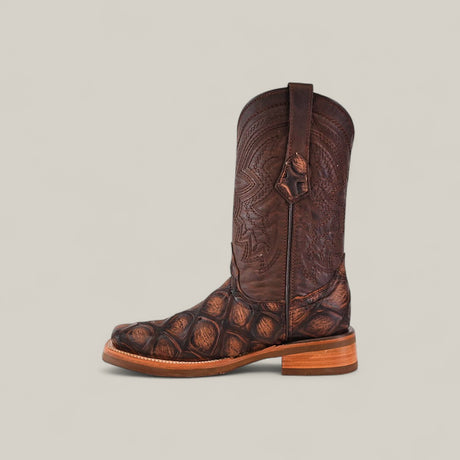 The Big Bass Pirarucu Print Rustic Brown - Rodeo Toe is shown in profile, featuring a rustic brown finish, distinctive pirarucu print on the foot, and detailed shaft stitching against a plain light background.