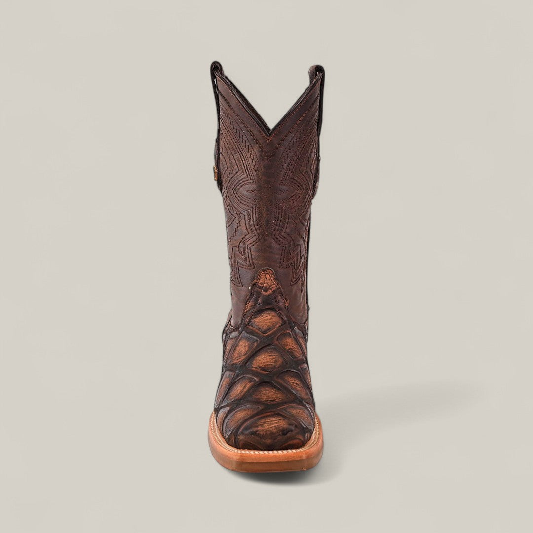 The Big Bass Pirarucu Print Rustic Brown - Rodeo Toe cowboy boot features intricate stitching and textured shaft and toe, shown from the front against a plain light gray background.