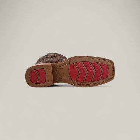 The Big Bass Pirarucu Print Rustic Brown - Rodeo Toe boot is shown from the bottom, highlighting its textured sole with red chevron treads and a red circular heel grip against a plain light background—ideal for Rodeo Toe fans.