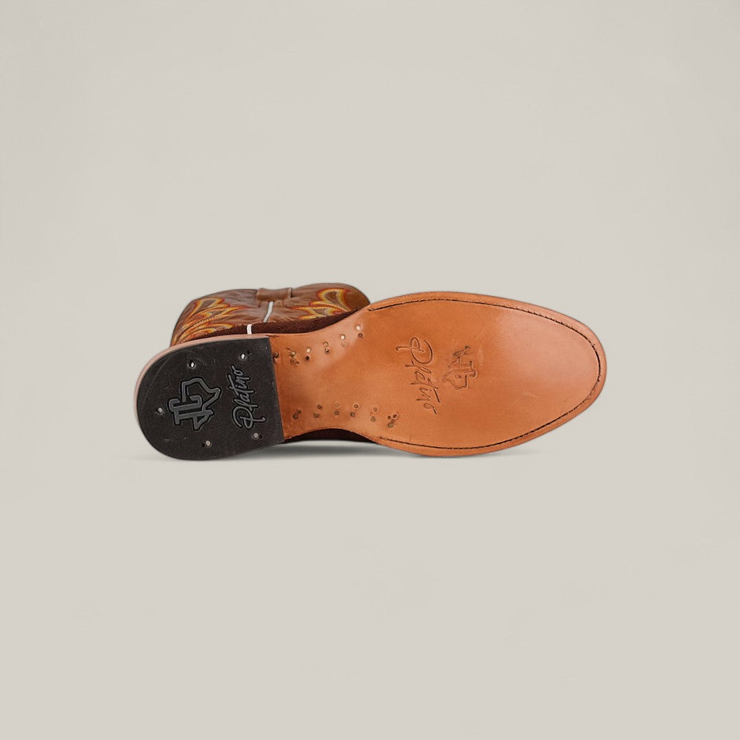 A Dusty - Classic Brown - Roper Toe boot lies on its side, showcasing the decorative stitched sole and signature details. The black heel features a white logo stamp, reflecting the timeless style of these classic boots.