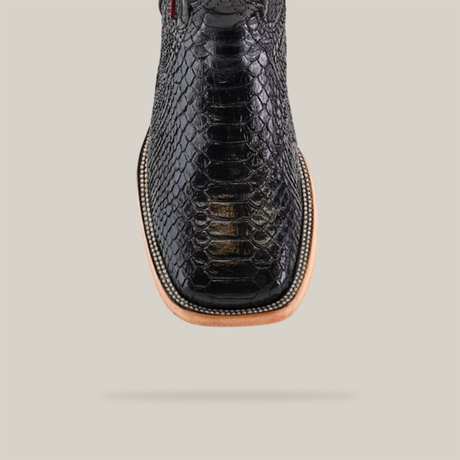 The Exotic Python - Black - Square Toe boot features a black crocodile-patterned design with a light brown sole, all set against a light gray background. The shoe is centered to highlight its detailed texture and elegant style.