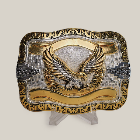 The Eagle Western Buckle features a stunning gold and silver palette with a majestic gold eagle at its center, wings spread wide. Its intricate border showcases classic western designs crafted in gleaming alpaca silver.