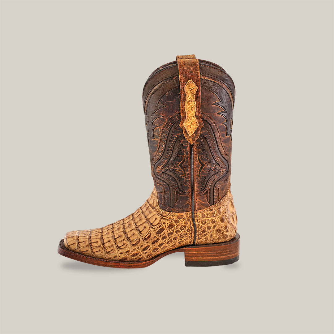 The Exotic Caiman Hornback - Antique - Rodeo Toe cowboy boot features genuine caiman leather with an intricate pattern in light tan and dark brown. It highlights a caiman hornback design on the lower and smooth leather upper, all set against a plain white background.