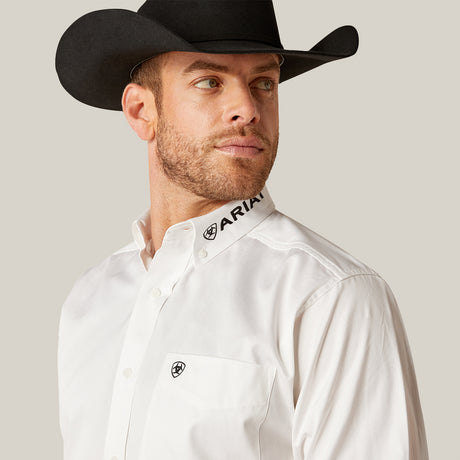 A bearded man looks to the side wearing a black cowboy hat and the Team Logo Twill Classic Fit Shirt White (10046825) by ARIAT. The shirt features ARIAT on the collar, embroidered details, and a small chest logo.