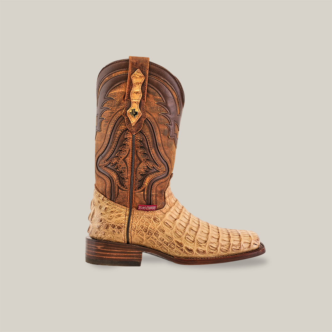 The Exotic Caiman Hornback - Orix - Rodeo Toe is a handcrafted cowboy boot made from premium leather with intricate brown designs and a tan textured lower mimicking Caiman skin, featuring a wooden heel and small red tag near the ankle, displayed against a plain white background.