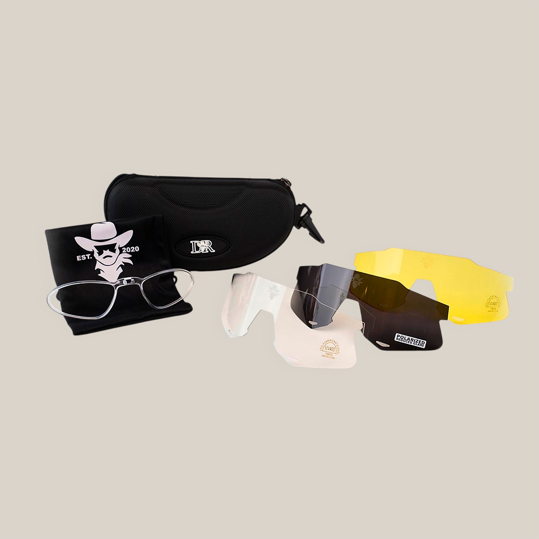 The DR Sport Sunglasses Ice Blue set includes a modern design with interchangeable clear, tinted, and yellow lenses. They come with prescription glasses and UV-protective shades, all in a stylish black case on a white surface with a branded microfiber cleaning cloth.